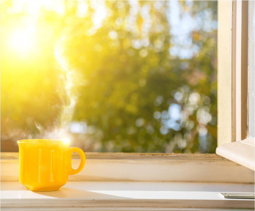 Yellow coffee mug on a sunlight window sill