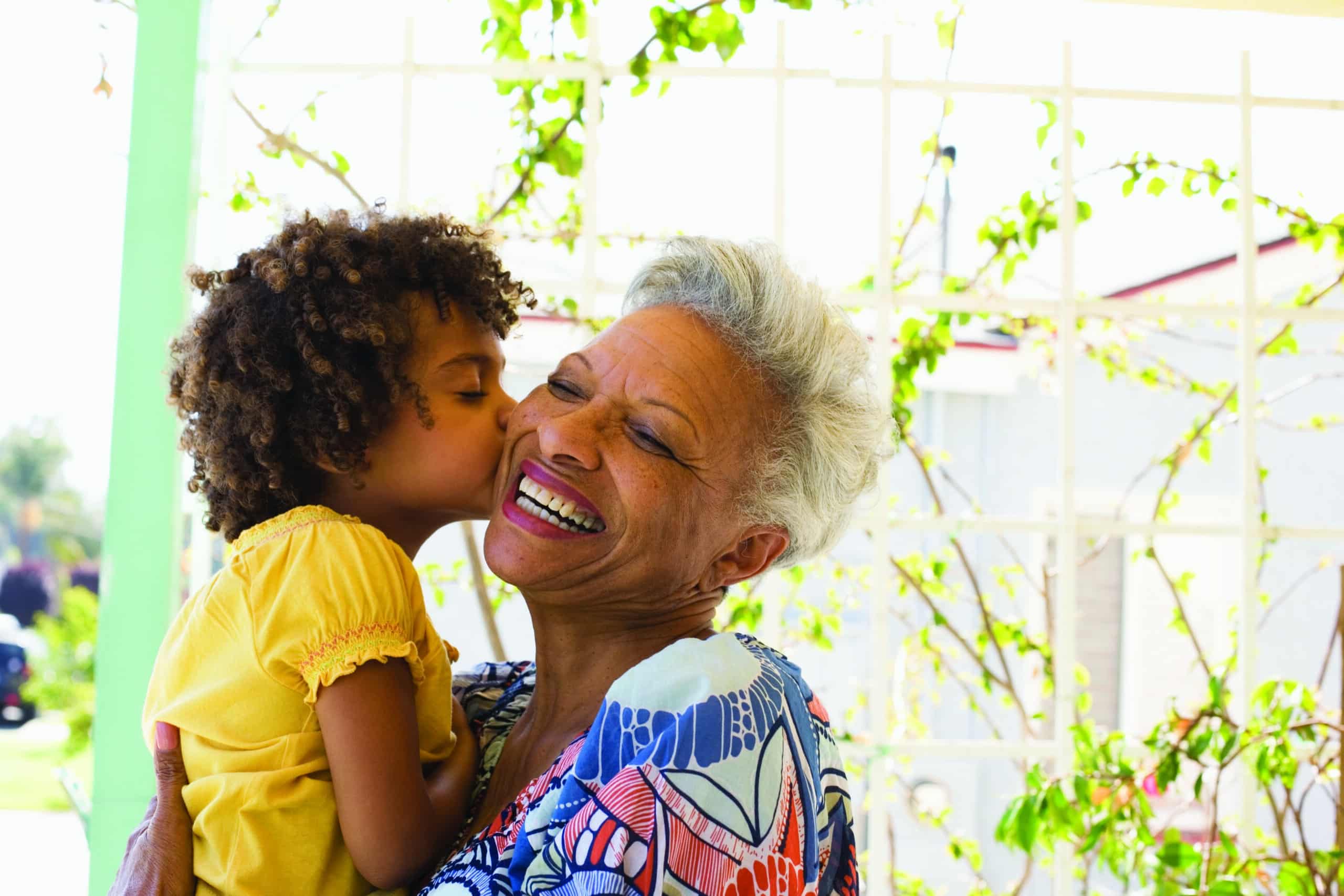 Granddaughter kissing the cheek of her retired grandmother in a beautiful outdoor garden